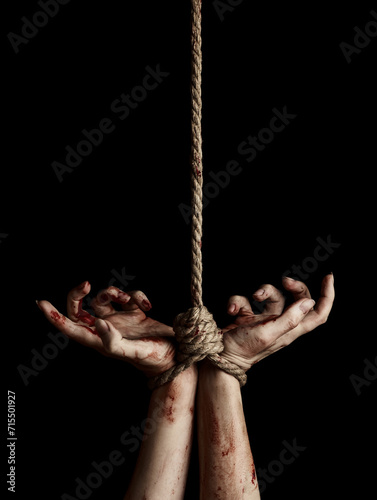 Woman hands with bloody stains tied with a rope over black background © Nik_Merkulov