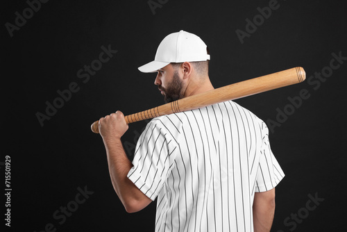Man in stylish white baseball cap holding bat on black background photo