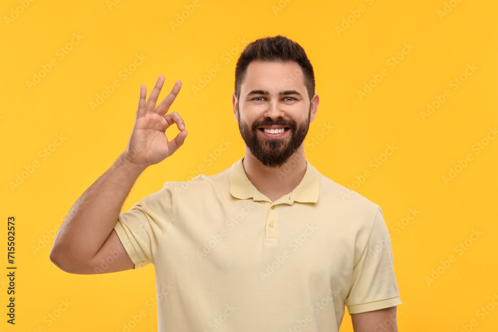 Man with clean teeth showing OK gesture on yellow background