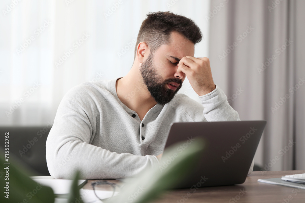 Man suffering from headache at workplace in office Man suffering from headache at workplace in office