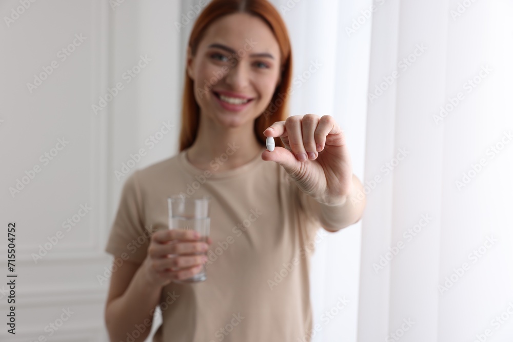Beautiful young woman with vitamin pill and glass of water, selective focus Beautiful young woman with vitamin pill and glass of water, selective focus