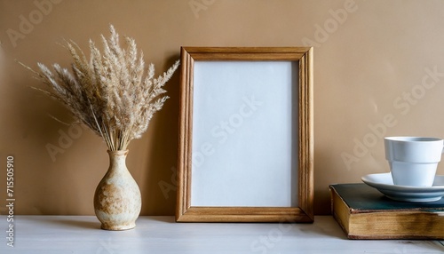 empty wooden picture frame mockup hanging on a beige wall background boho shaped vase with dry flowers on the table cup of coffee and old books perfect for working space and home office ideal for