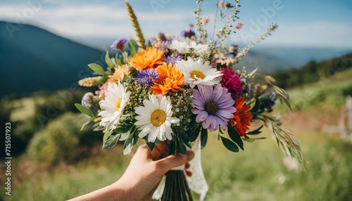a close up of a bride s hand holding a delicate bouquet of wildflowers featuring a mix of vibrant blooms and natural foliage against a clean and minimalistic background photo
