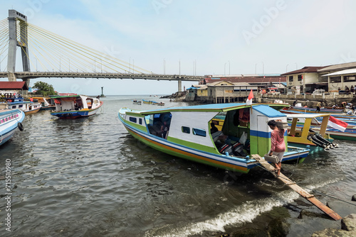 Covered ferry boats in Manado port with the Soekarno Bridge beyond in provincial capital of Sulawesi's far north, Manado, North Sulawesi, Indonesia, Southeast Asia photo