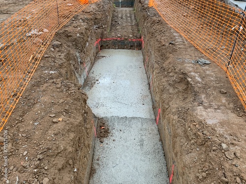 Base of a strip foundation protected with a construction fence. Continuous footing in a construction site. Health and safety fence to avoid falling from different heights.