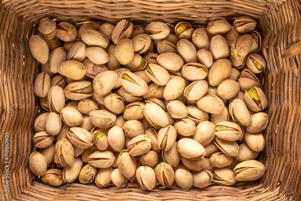 A small amount of delicious pistachios in a basket, macro, top view.