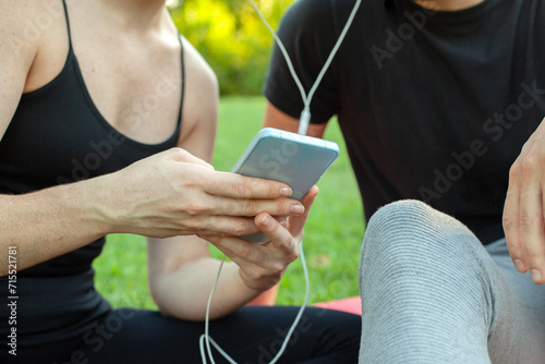 Chica compartiendo música con un chico en su móvil. Pareja escuchando música en un parque. Amigos. al aire libre. photo