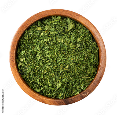 Dried parsley in a wooden bowl isolated on white background. Parsley with copy space for text. Dried herbs isolated on white. Parsley spice leaves on white background.