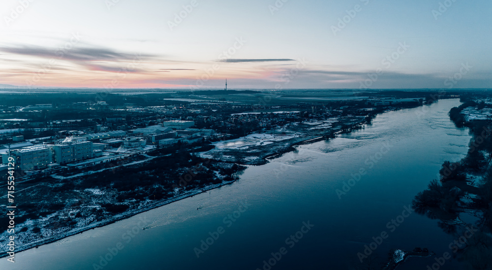 Aerial View of a City during sunset reflecting in a calm river