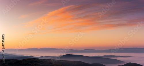 panorama of a sky above the carpathian mountain range with fog in the valley at dawn. clouds in red and orange colors of a rising sun