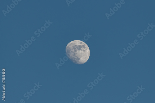 Waning moon in the blue sky during the day