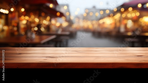 Empty wooden surface with a backdrop of a bustling street market illuminated by warm  blurry lights at twilight.