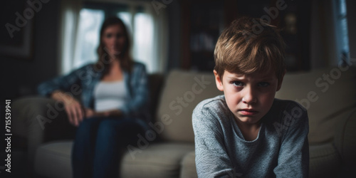 A portrait of a troubled young boy with a look of concern, with a blurred figure of a parent behind.