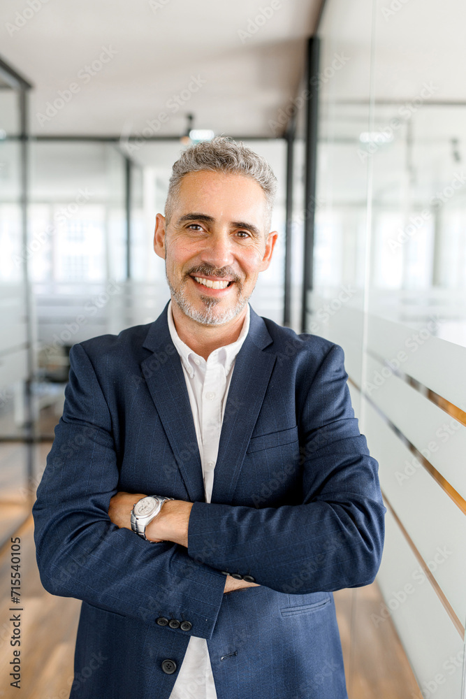Standing in a bright corridor, a mature businessman presents a portrait of professionalism and accessibility, embodying the dynamism of the modern work environment Standing in a bright corridor, a mature businessman presents a portrait of professionalism and accessibility, embodying the dynamism of the modern work environment