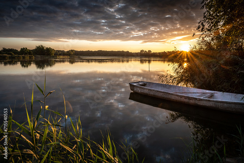 cudowny wschód słońca nad jeziorem i łódka przy brzegu
