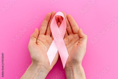 Pink ribbon symbol of breast cancer with hands. Medical support and prevention