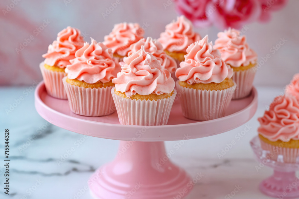 An elegant arrangement of homemade cupcakes with fluffy pink frosting, presented on a stylish pink cake stand against a marble backdrop