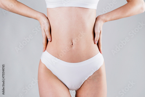 Close up shot of unrecognizable fit woman beige in lingerie isolated on white background. Torso of slim attractive female with flat belly in beige underwear. Copy space for text.
