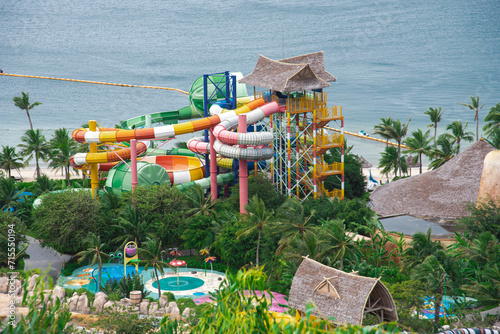 Close-up beach side water park colorful slides ride tropical themed family aquapark lush green coconut palm trees in Nha Trang, Vietnam photo