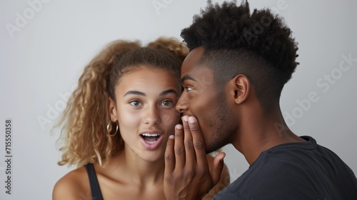 African american man wispering something to caucasian woman's ear on neutral background scheming something