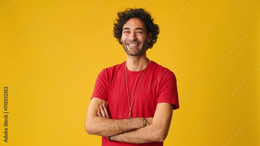 Happy man crossing his arms and looking at camera isolated on yellow background in studio Happy man crossing his arms and looking at camera isolated on yellow background in studio