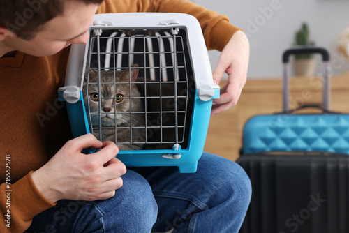 Travel with pet. Man holding carrier with cute cat indoors, closeup. Space for text