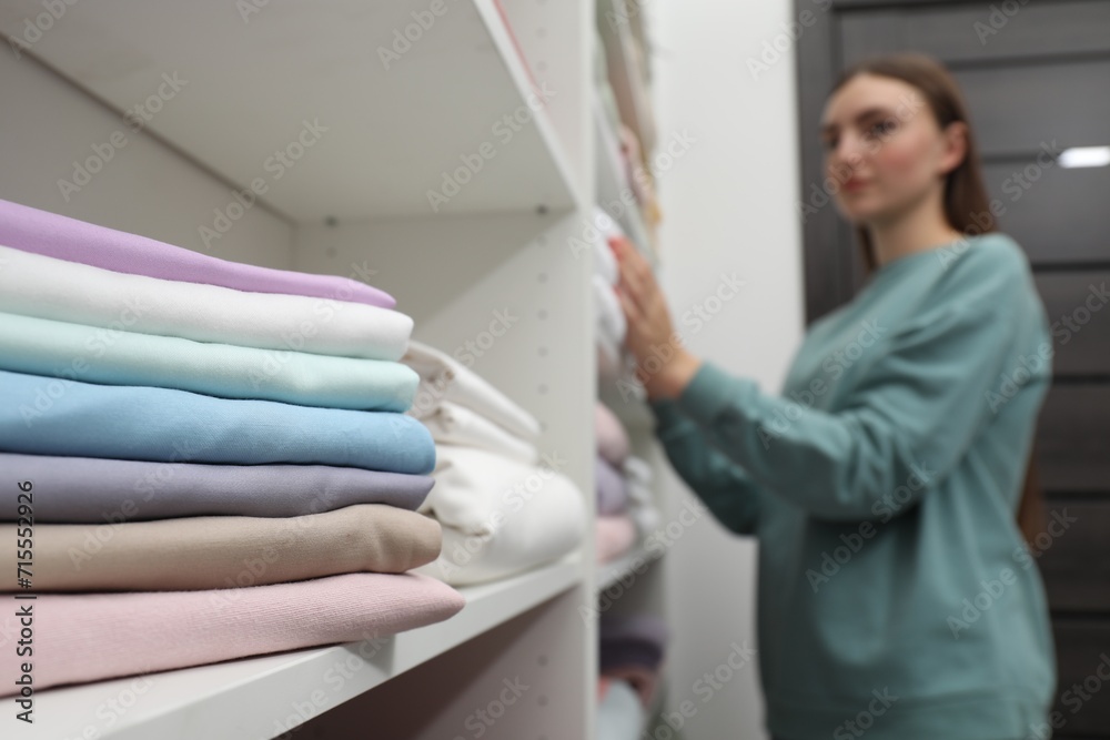Stack of bed linens on shelf in shop. Customer choosing bedding indoors, selective focus Stack of bed linens on shelf in shop. Customer choosing bedding indoors, selective focus