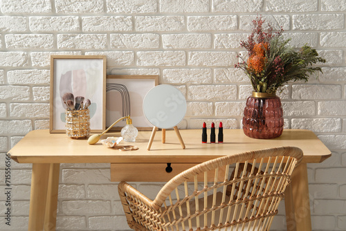 Mirror, makeup products and perfume on dressing table in room