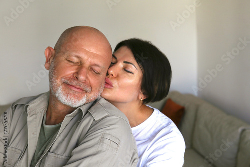 Portrait of affectionate adult couple hugging at home, expressing the love to each other. Close up, copy space, background.