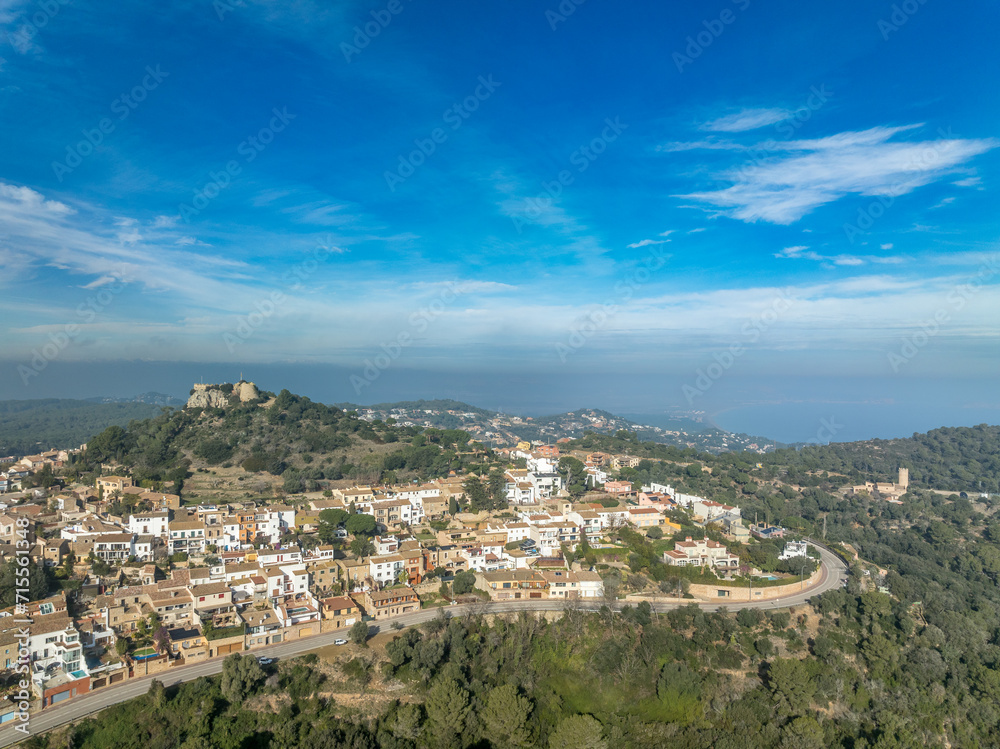 Aerial view of 16th-century Begur castle fort atop a forested hill, with panoramic views of the Mediterranean Sea. Watch towers built against the pirates