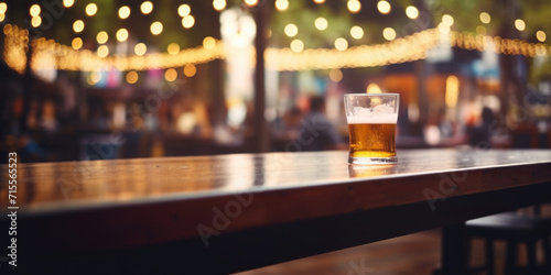 A refreshing glass of beer on a wooden table with blurred festive lights creating a cozy outdoor evening atmosphere.