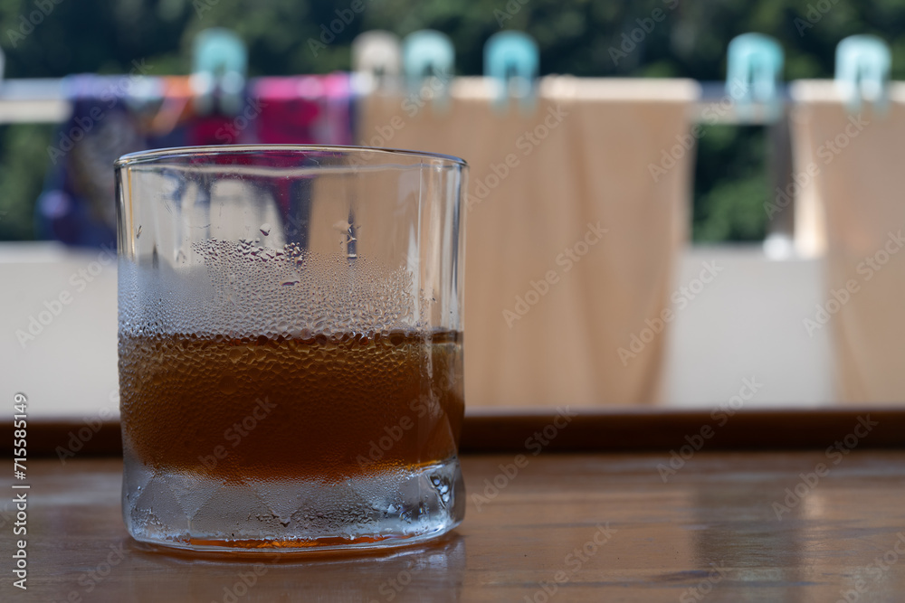 a cold glass of icetea with water droplets from condensation
a cold glass of icetea with water droplets from condensation