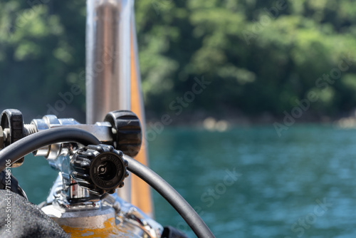 The head of a compressed air cylinder for diving from a liveaboard with the green of a island in the background.
