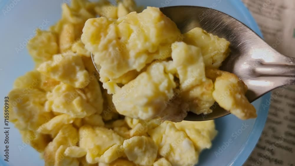 Closeup of man eating egg bhurji or scrambled egg dish with spoon inside home popular street food and a breakfast Closeup of man eating egg bhurji or scrambled egg dish with spoon inside home popular street food and a breakfast