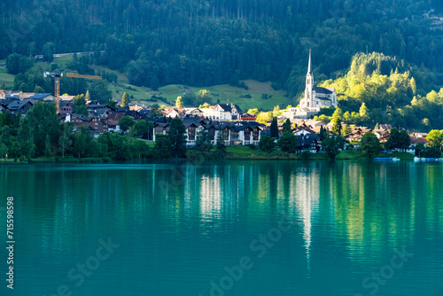 Swiss village Lungern with traditional houses, old church Alter Kirchturm along lovely emerald green lake Lungerersee, canton of Obwalden Switzerland