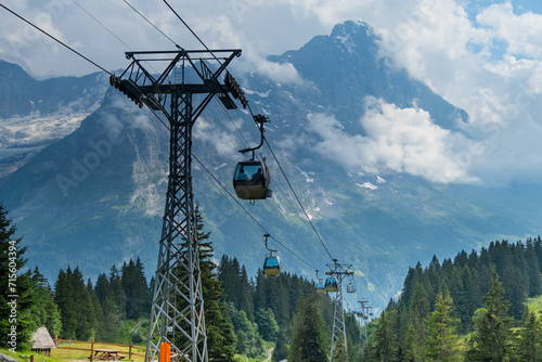 Cable car in Swiss Alps. Gondola from Grindelwald in Jungfrau. Summer Alpine landscape with snowcapped mountains background. Transport tourists uphill