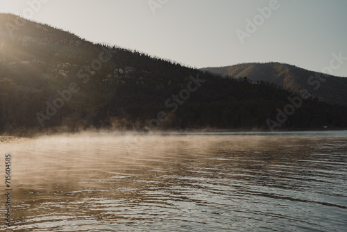 Morning fog lit up by the sun with mountains in the background photo