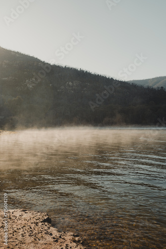 Morning fog lit up by the sun with mountains in the background photo