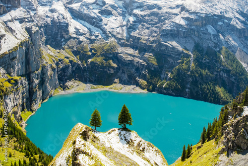 Idyllic morning view of the lake Oeschinensee. Location Swiss alps, Switzerland, Kandersteg district. Blue mountain lake with pine trees and mountains in background.