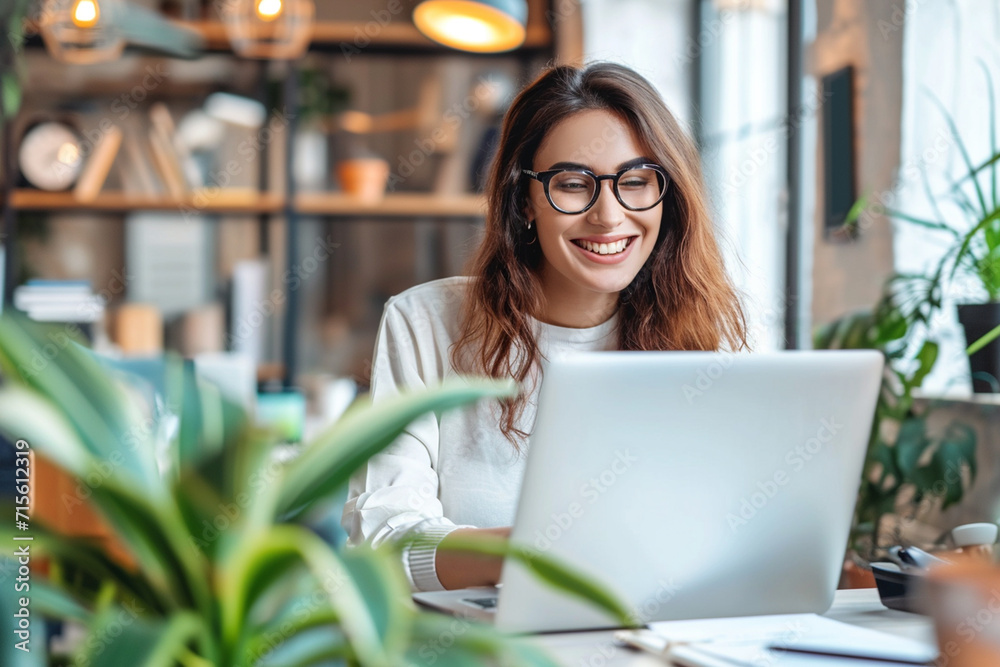 Young business woman working in laptop and smiling looking at camera Young business woman working in laptop and smiling looking at camera