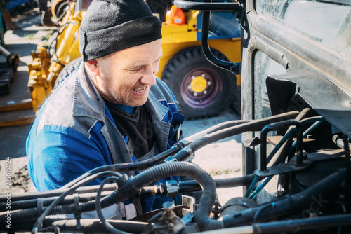 Mechanic repairs engine of tractor or heavy equipment. Farmer inspects and diagnoses agricultural machinery.