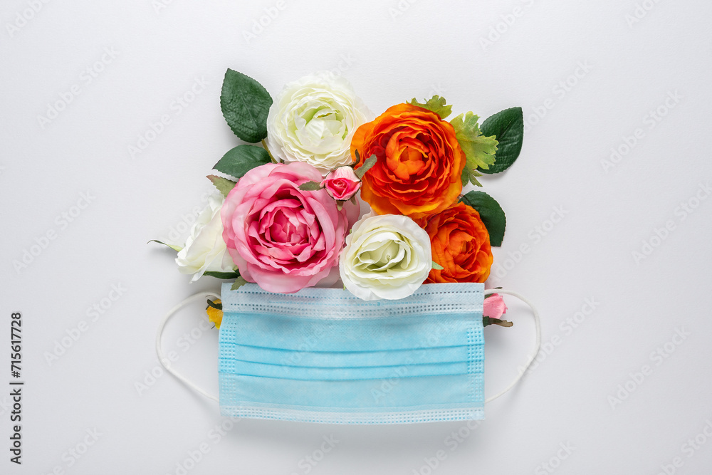 Medical mask with different color flowers on white background. Minimal spring concept.