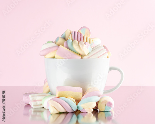 Marshmallows colorful chewy candy in a cup on pink background. Sweet holiday food concept.