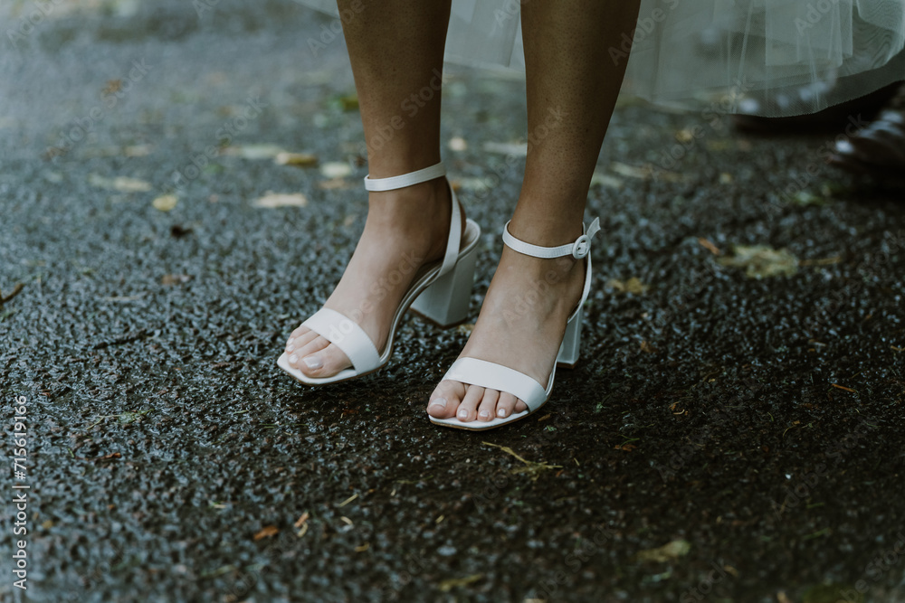 Slender womans feet in bridal or white shoes standing on the ground with her dress hitched up Slender womans feet in bridal or white shoes standing on the ground with her dress hitched up