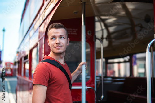 Portrait of tourist boarding to red double-decker bus in central London. United Kingdom.. photo