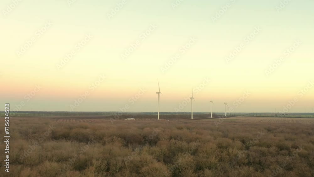 Aerial view of powerful Wind turbine farm for energy production on beautiful cloudy sky at highland. Wind power turbines generating clean renewable energy for sustainable development. 4k footage. Aerial view of powerful Wind turbine farm for energy production on beautiful cloudy sky at highland. Wind power turbines generating clean renewable energy for sustainable development. 4k footage.