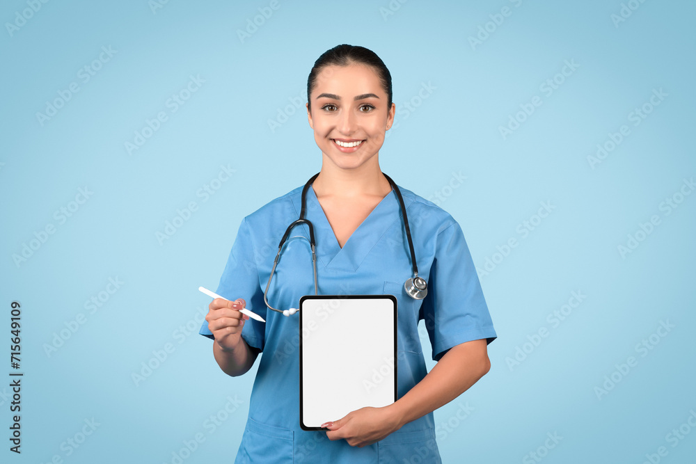 Happy young female nurse presenting digital tablet with blank screen, ideal for healthcare apps or medical offers Happy young female nurse presenting digital tablet with blank screen, ideal for healthcare apps or medical offers