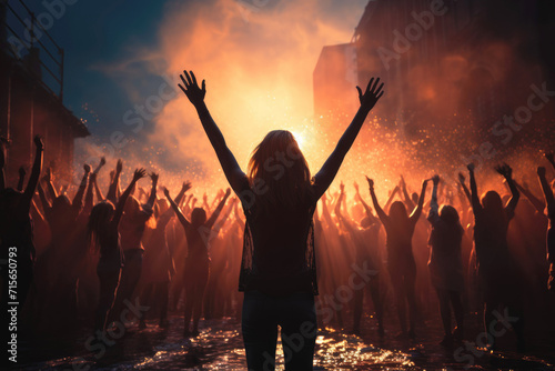 Silhouettes of woman with raised hands at sunset, festive mass event, joy. © Katerina Bond