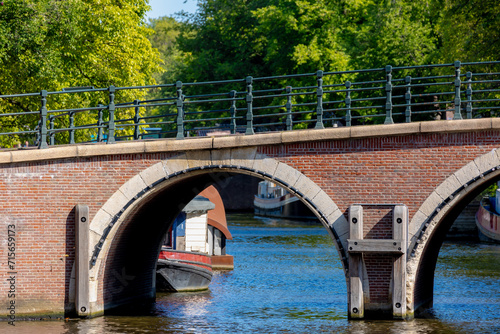 Summer cityscape, Canals of Amsterdam, Under view of brick bridge and railing, Still water and soft sunlight in the afternoon, Canal cruises is very famous activities, Tourist attraction, Netherlands.