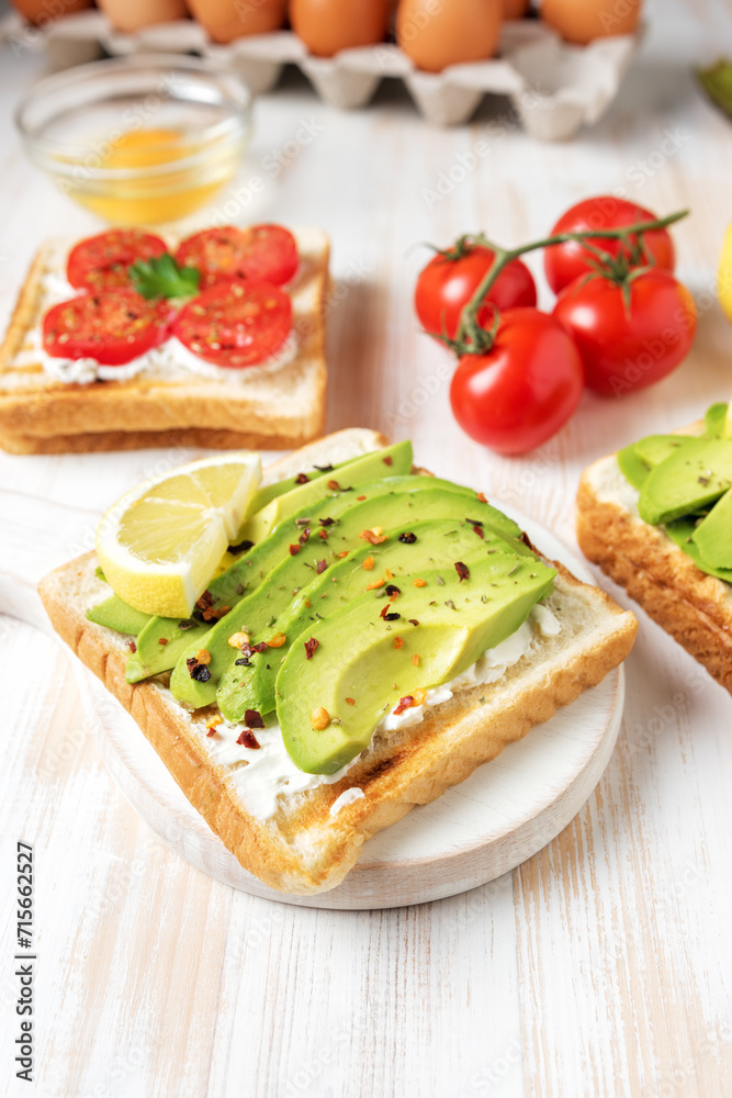 Sliced avocado on toast bread with spices on white wooden background. Food concept.